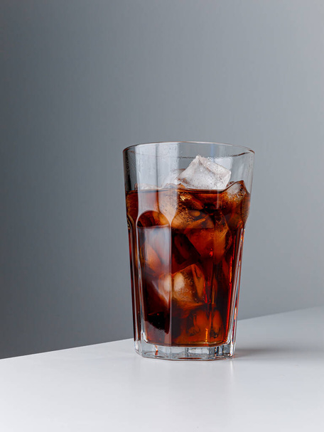 Cola with Ice Cubes. Glass of cola. Copy Space. Pour soft drink in glass with ice splash on dark background. glass of cola with ice isolated. Soft drink glass with ice splash on cool smoke background. - Fotoğraf, Görsel