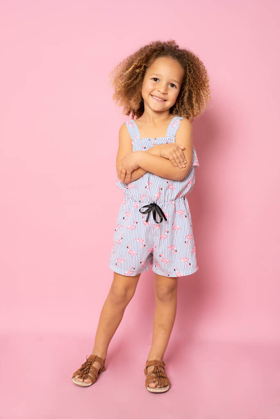 Full length photo of excited charming cute little girl with her hands folded standing over pink background. - Fotó, kép
