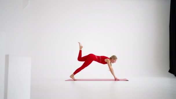 Young woman shows yoga or pilates exercises. Young attractive woman practicing yoga in studio. Girl shows different poses for yoga in white background. Healthy lifestyle, yoga in my heart, sports - Filmmaterial, Video