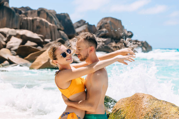 Foto de hermosa pareja joven en la playa abrazando. Joven hombre y mujer juntos en una playa tropical
. - Foto, Imagen