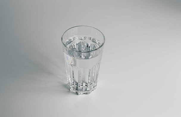 A faceted glass of pure water on light grey background. Copy space. - Photo, Image