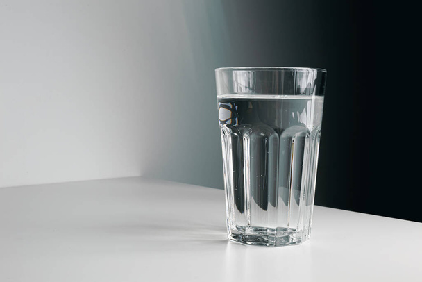 A faceted glass of pure water on light grey background. Copy space. - Photo, Image