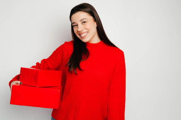 De jonge vrouw met haar cadeautjes in rode dozen die ze ontving voor Valentijnsdag. Het meisje lacht aangenaam en ziet er gelukkig uit - Foto, afbeelding