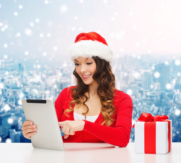 smiling woman in santa hat with gift and tablet pc - Photo, image