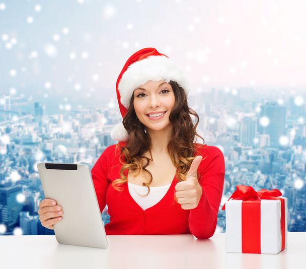 smiling woman in santa hat with gift and tablet pc - Foto, immagini