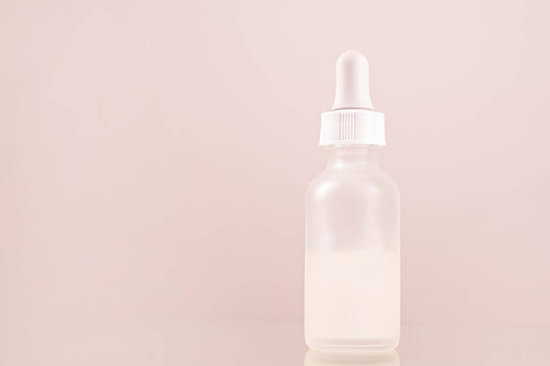bouteille de verre compte-gouttes d'huile sérum visage avec pipette sur fond rose gros plan - Photo, image