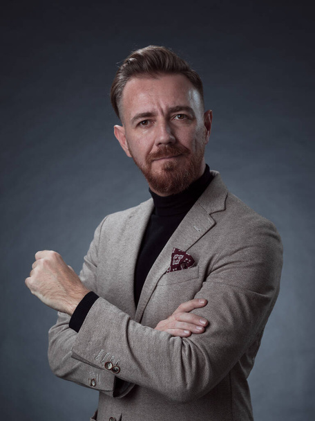 Portrait of a stylish elegant senior businessman with a beard and casual business clothes in photo studio isolated on dark background gesturing with hands. High quality photo - Zdjęcie, obraz