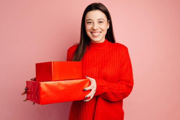 The girl has straight black hair and wearing the red sweater. The girl is smiling with a broad smile and holding red boxes - Fotografie, Obrázek