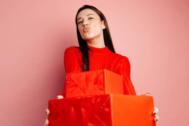 Chica en el suéter rojo y cajas de regalo rojas. Ella es feliz y alegre y celebra el Día de San Valentín - Foto, Imagen