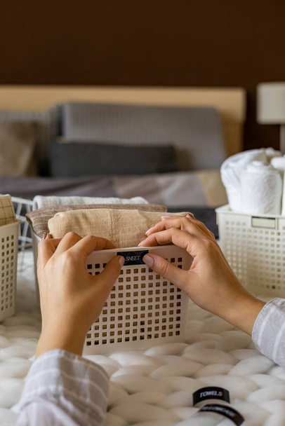Woman hands neatly folded linens and towels use Marie Kondo method with sticky label tags - Foto, Imagen