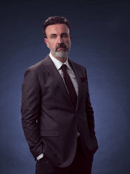 Portrait d'un élégant homme d'affaires élégant avec une barbe et des vêtements d'affaires décontractés dans un studio photo isolé sur fond sombre gesticulant avec les mains. Photo de haute qualité - Photo, image