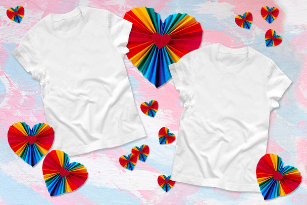 Makieta dwóch identycznych białych T-shirtów z wystrojem Walentynki w postaci serc w kolorach tęczy LGBTQ. Parowane białe bawełniane t-shirty makieta do promocji projektu - Zdjęcie, obraz