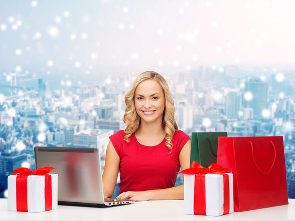 smiling woman in red shirt with gifts and laptop - Valokuva, kuva