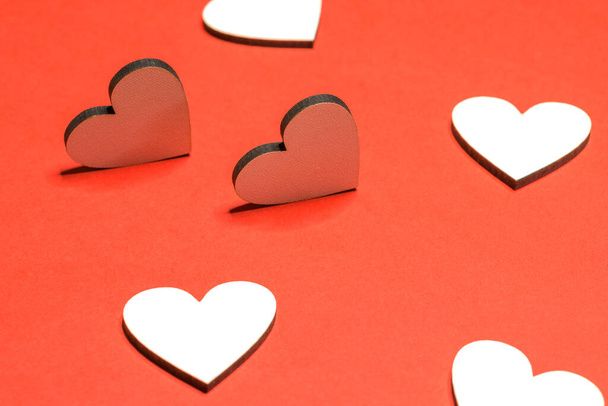 Liebeshintergrund mit winzigen Holzherzen auf rotem Plakatkarton-Papier. Valentinstag-Konzept. - Foto, Bild