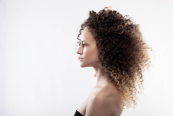 Beautiful brunette girl with long curly hair. Studio portrait on white background - Fotó, kép