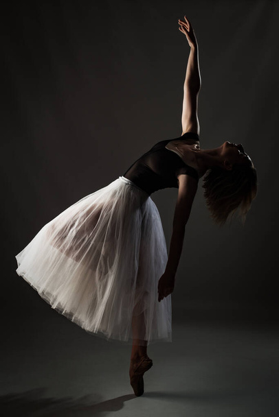 ballerina with a white dress and black top posing on gray background - Фото, изображение