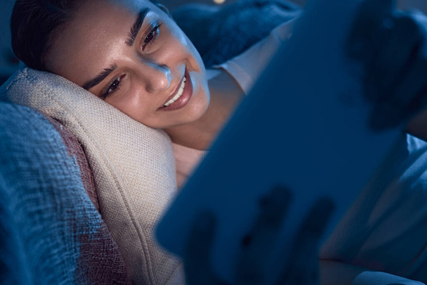 Content woman watching movie on tablet in bed - Photo, Image