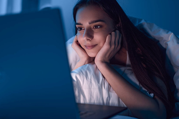 Content woman watching movie on laptop at night - Фото, зображення