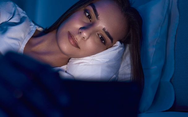 Woman using smartphone in bed with before sleep - Foto, afbeelding