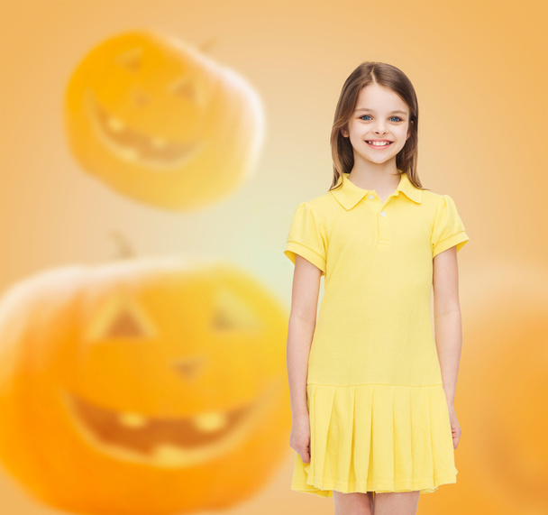 smiling girl in dress over pumpkins background - Фото, изображение