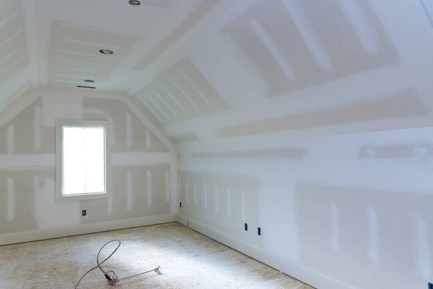 Wykończenie tynkowania ścian gipsowo-kartonowych gotowych do malowania nowym domem w budowie - Zdjęcie, obraz