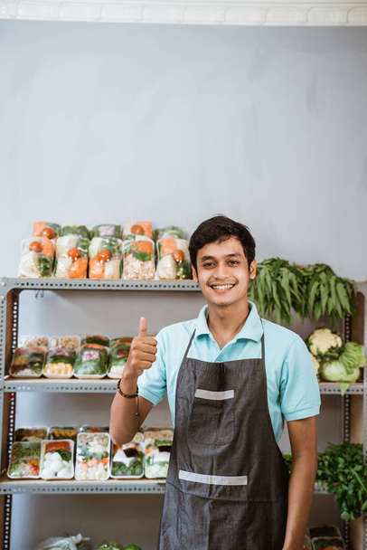 Smiling man with thumbs up with vegetable products background - Foto, Bild