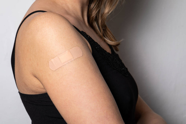 Védőoltás egy nő vállán. Orvosi tapasz a bőrön - Fotó, kép
