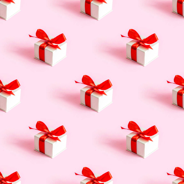 Pequeña caja de regalo envuelta blanca repita el patrón sin costuras sobre un fondo rosa claro. Día de San Valentín, Cumpleaños, Papel de regalo sorpresa del día de las madres. - Foto, Imagen