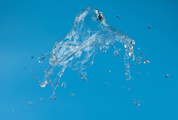 a splash of clear, transparent water with drops on a blue background. - Foto, afbeelding