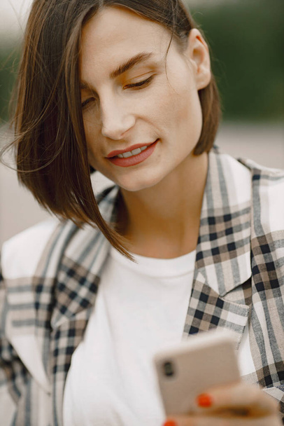 Portrait of a young brunette woman using a mobile phone outdoors - Photo, image