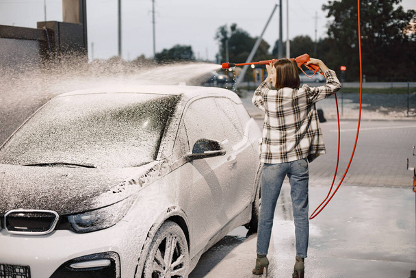 Woman washing her car in the car wash station - 写真・画像