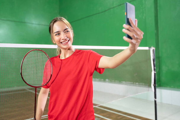 Female badminton player in red selfie with a smartphone - Fotoğraf, Görsel