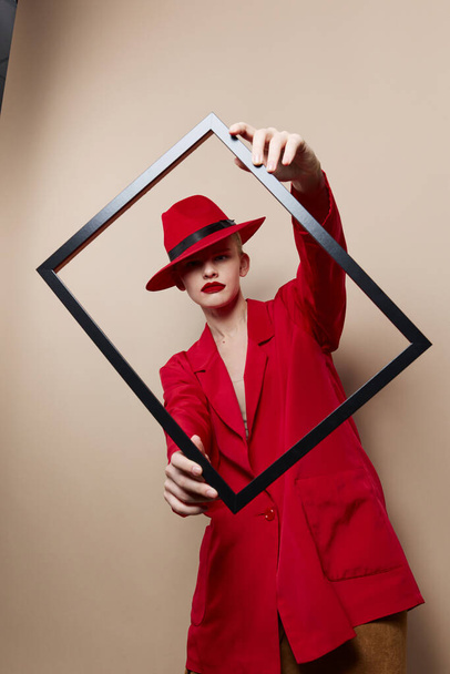 mujer glamorosa con marco de madera posando traje rojo modelo de estudio inalterado - Foto, imagen