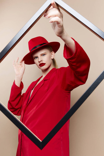 modieuze vrouw frame in de hand in rode hoed en jas Lifestyle poseren - Foto, afbeelding