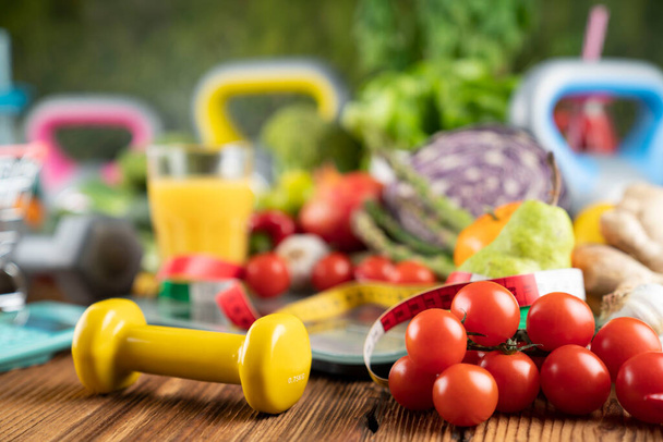 Concept de fitness. Alimentation saine : fruits et légumes. Équipement pour les exercices de fitness : peseuse et haltères sur table en bois rustique. - Photo, image