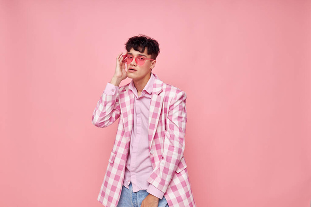 A young man pink glasses checkered jacket fashion posing pink background unaltered - Фото, зображення