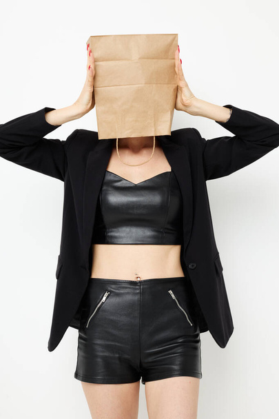 beautiful woman in a leather suit black jacket with a bag on his head isolated background - Photo, image