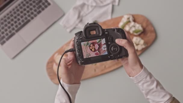 Top view shot of unrecognizable female food photographer with camera taking pictures of beautifully arranged blue cheese bruschetta with tomatoes and figs on wooden plate - Filmati, video