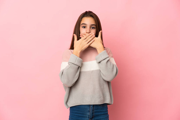 klein meisje geïsoleerd op roze achtergrond bedekking mond met handen - Foto, afbeelding