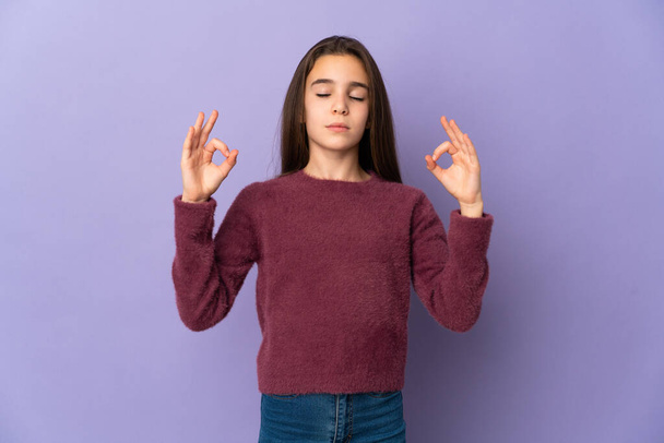 Little girl isolated on purple background in zen pose - Foto, afbeelding
