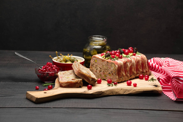 Traditional French terrine covered with bacon on dark wooden background - Фото, изображение