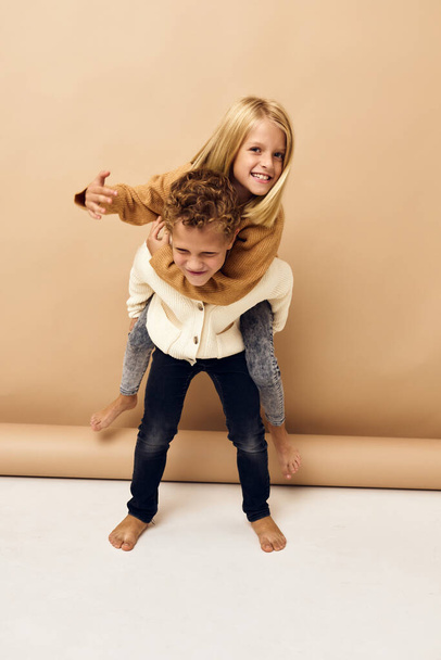 брат і сестра разом у светрах веселий повсякденний одяг бежевий фон
 - Фото, зображення