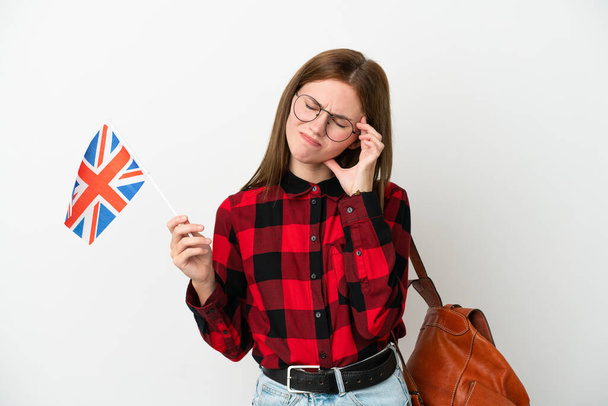 Mladá žena drží vlajku Spojeného království izolované na modrém pozadí s bolestí hlavy - Fotografie, Obrázek