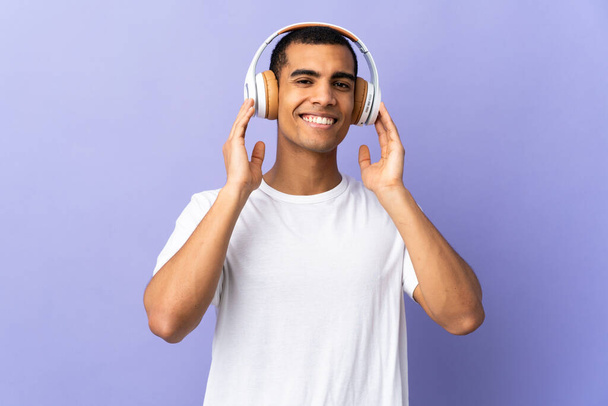 African American man over isolated purple background listening music - Foto, Imagem