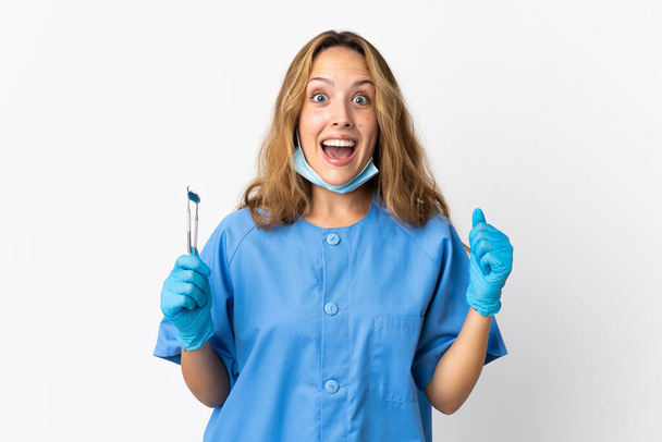 Woman dentist holding tools isolated on white background celebrating a victory in winner position - Foto, immagini