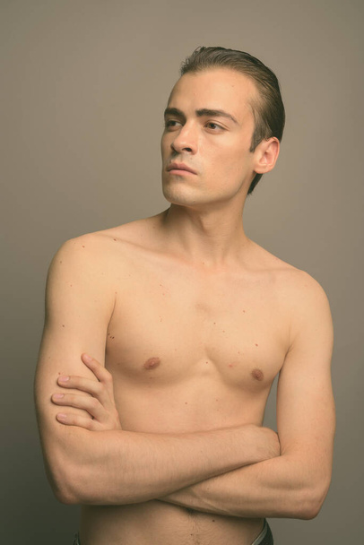 Студійний знімок молодого красивого чоловіка без сорочки на сірому фоні
 - Фото, зображення