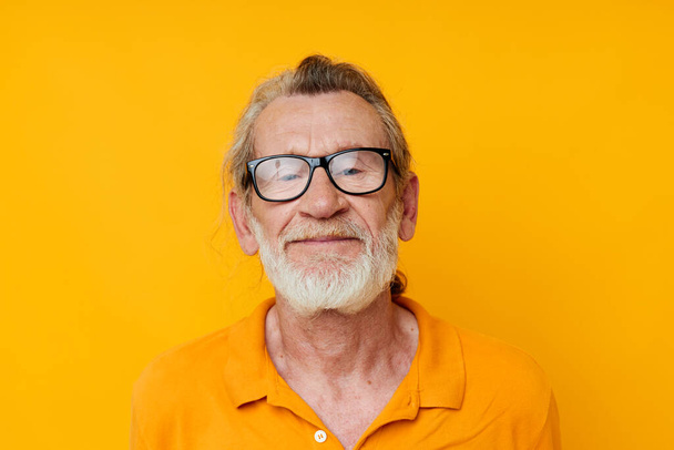 an elderly man with glasses in a yellow t-shirt with glasses close-up - Фото, изображение