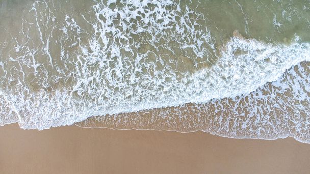 Antenni drone näkymä kohtisuorassa sininen aallot kaatuu hiekkarannalla rannikolla. Isku märkä vaha luo valkoista vaahtoa. Talviranta on tyhjä. - Valokuva, kuva