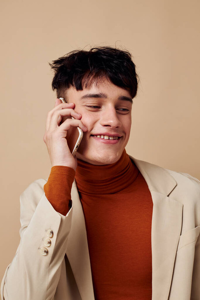 pohledný chlap pózuje s telefonem v ruce v bundě elegantní styl Lifestyle beze změny - Fotografie, Obrázek
