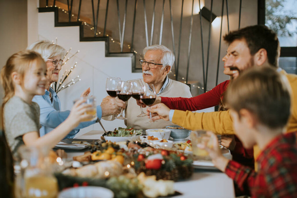 Mutlu bir aile evde kırmızı şarapla yemek yiyor. - Fotoğraf, Görsel